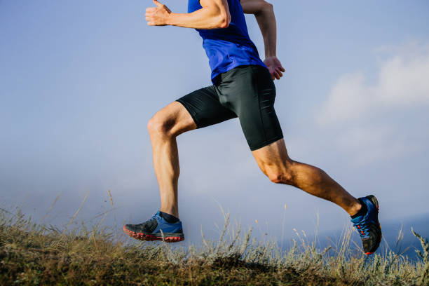 gambe muscolose corridore pista di corsa su erba secca - cross country running track and field sports event running foto e immagini stock