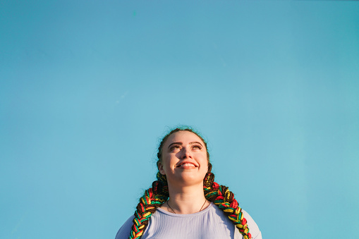 Young Maori woman looking up in front of light blue background in Auckland, New Zealand.