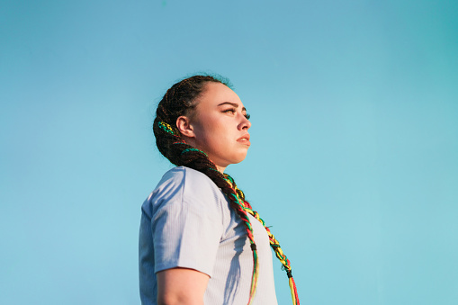 Young Maori woman looking away in front of light blue background in Auckland, New Zealand.