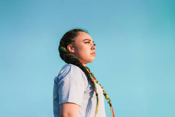I am strong and confident. Young Maori woman looking away in front of light blue background in Auckland, New Zealand. maori weaving stock pictures, royalty-free photos & images