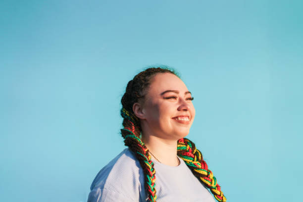 Young Maori woman looking away in front of light blue background in Auckland, New Zealand.
