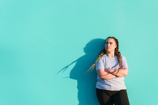 Portrait of young Maori woman against teal background wall.