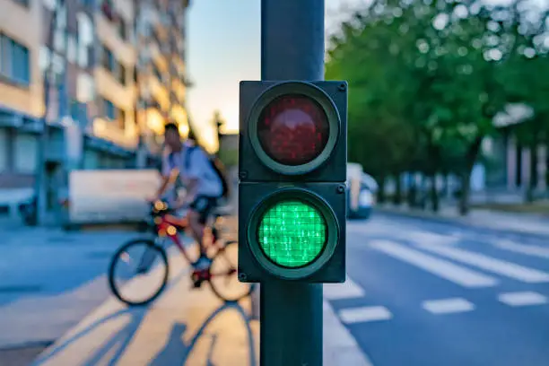 Vitoria-Gasteiz. Basque country, Spain. Green traffic light and defocused cyclist crossing crosswalk at sunset