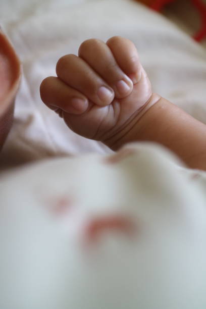 a photo of one hand of a newborn in a grasping position with the thumb inside