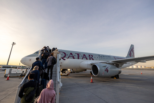 Doha, Qatar - February 21, 2023 : Passengers board an Airbus A320 aircraft, operated by Qatar Airways at Hamad International Airport in Doha, Qatar.