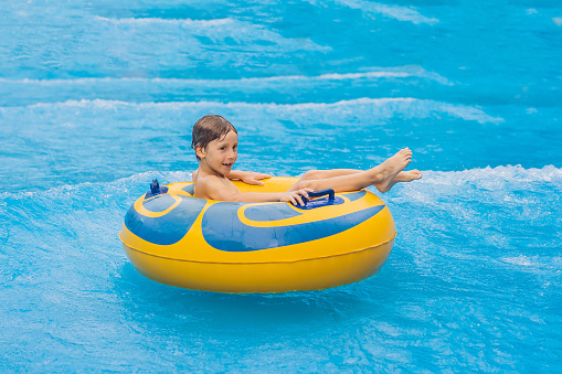 Niño en una piscina flotando sobre olas artificiales en un parque acuático photo