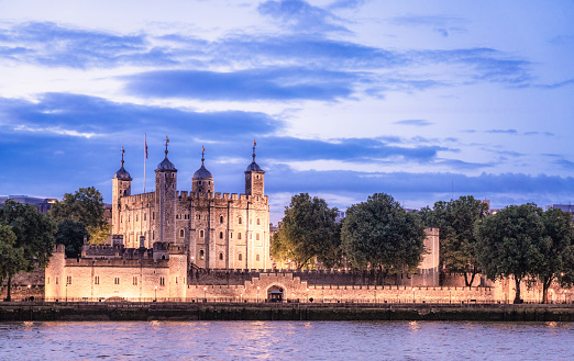 Looking across the Thames to the historic Tower Of London, illuminated as the light fades at dusk.