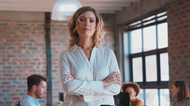 Portrait Of Serious Businesswoman In Office With Colleagues Working In Background