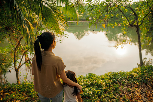 Mother and daughter watching sunset at park. People and Nature