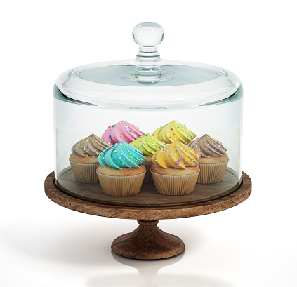 Glass domed cake plate or punch bowl with colorful cupcakes isolated on white.