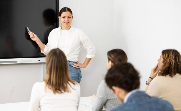 istock Young female professor explaining subject to classroom full of students 1470691095