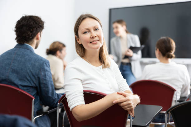 istock Positive middle-aged woman turning around and looking at camera during advanced training course in auditorium 1470691197