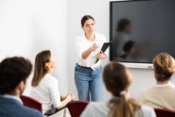 istock Young female professor explaining subject to classroom full of students 1470691230