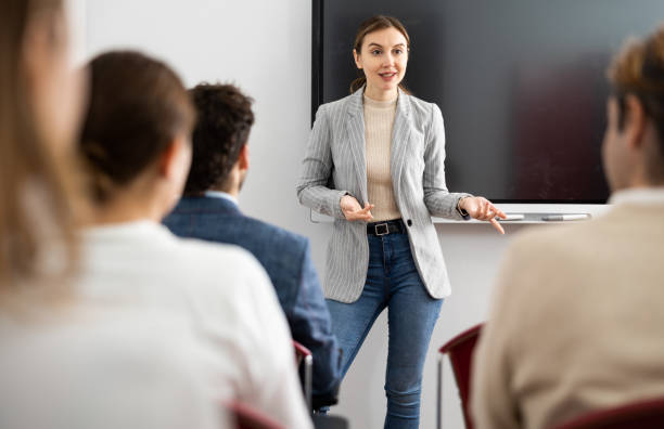 Young female tutor teaching students in college classroom