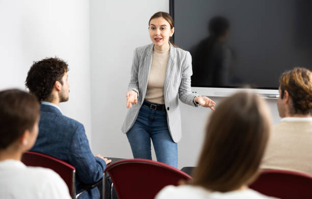 istock Positive skilled female coach explaining topic to group of people during foreign language class in auditory 1470691234