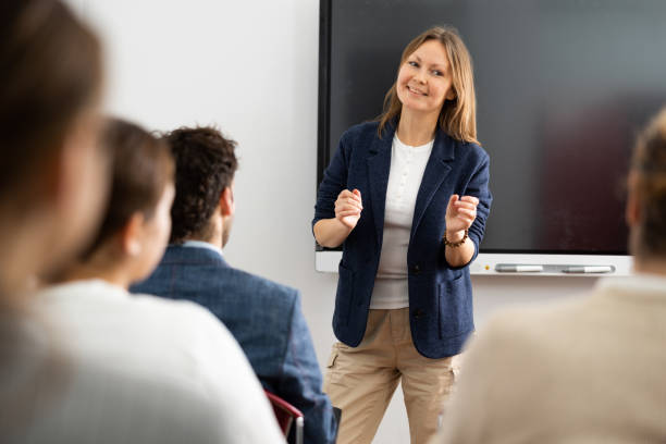 istock Middle-aged woman standing near interactive board and communicating with adult students during foreign language class 1470691236