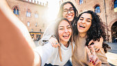 Three young women taking selfie picture with smart mobile phone on city street - Happy beautiful female friends smiling at camera outdoors -  Life style concept with cheerful girls enjoying vacation