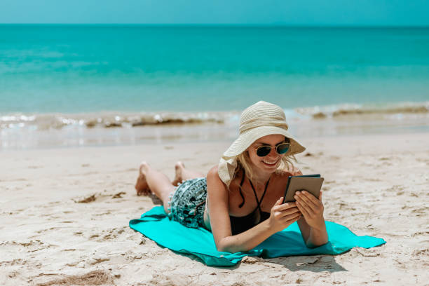 istock Woman Relaxing at Beach on Chair with Electronic Book Reader 1470692079