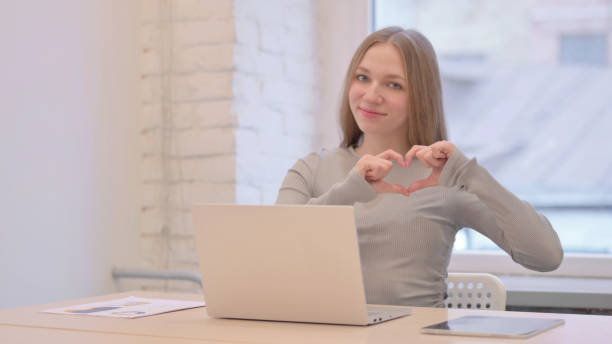 istock Young Woman Showing Heart Sign while using Laptop 1470695508