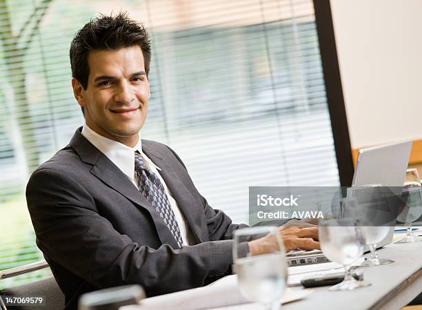 Lächelnd Geschäftsmann Sitzt Am Tisch Mit Laptop Stockfoto und mehr Bilder von Anzug - Anzug, Arbeiten, Bildschärfe