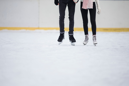 Legs of Young Caucasian Couple in Winter With Ice Skates Posing Together Over a Snowy Winter Surface Holding Hands Together. Horizontal Iage