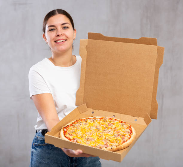 istock Smiling young woman holding pizza box 1470696670