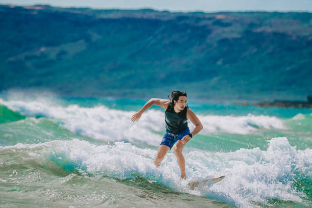 Asian Chinese Male Surfer riding wave in Pacific Ocean