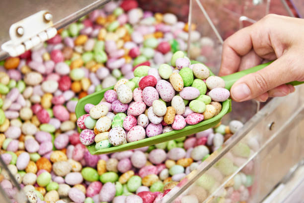 istock Hand with scoop peanut dragee in colored glaze in shop 1470697129