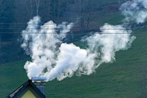 dense wood smoke from chimney on the roof