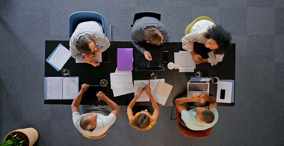 Overhead view of business people discussing strategy with each other during meeting in office.