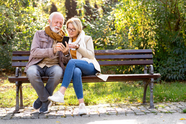 istock Cheerful elderly couple using banking apps on a smartphone to make payments outdoors in the park 1470699380