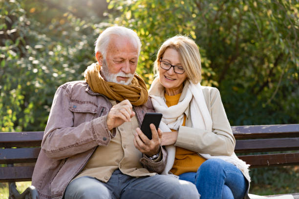 istock Cheerful elderly couple using banking apps on a smartphone to make payments outdoors in the park 1470699540