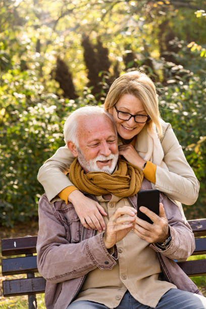istock Cheerful elderly couple using banking apps on a smartphone to make payments outdoors in the park 1470699545