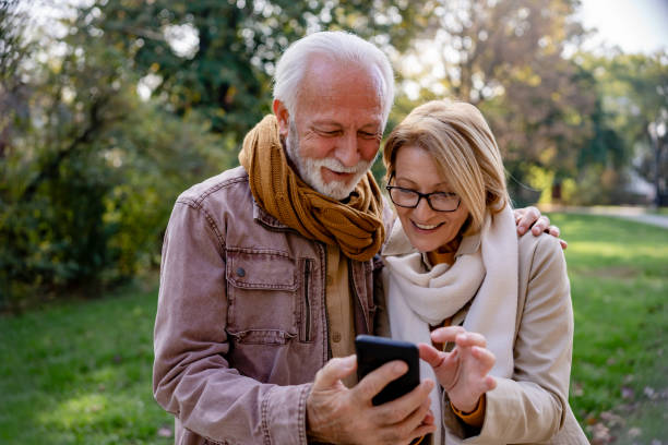 istock Cheerful elderly couple using banking apps on a smartphone to make payments outdoors in the park 1470699887