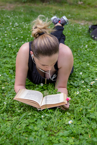Smiling woman relaxing in grass and reading a book