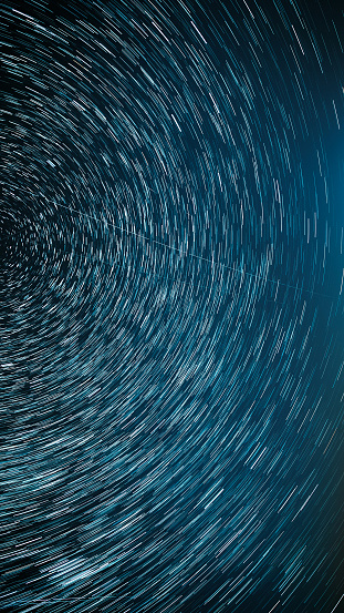 Night Starry Sky Stars And Meteoric Track Trails. Meteors Fly Across Sky. Spin Trails Of Stars. Star Trails On Night Sky Background. Dark Blue . Amazing Stars Effects In Sky. Stars Rotate Of Background. Large Exposure. .