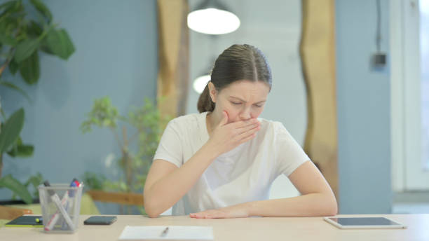istock Coughing Sick Young Woman Sitting in Office 1470700818