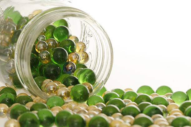 Green and Gold marbles spilling out of a jar.