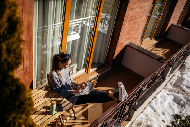 Young woman using laptop on balcony at morning