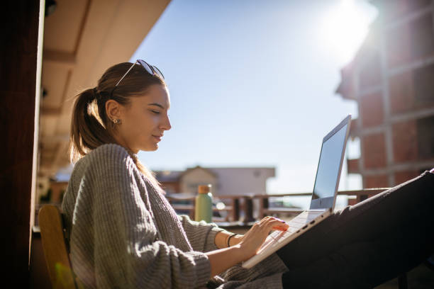 istock Young woman using laptop on balcony at morning 1470708938