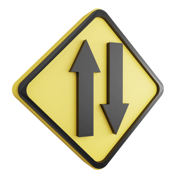 A close-up of a priority road sign, consisting of a yellow diamond and a black cross on a white background, positioned near a residential building. The sign is set against a backdrop of greenery and the side of a white building, indicating a key intersection in a suburban area.