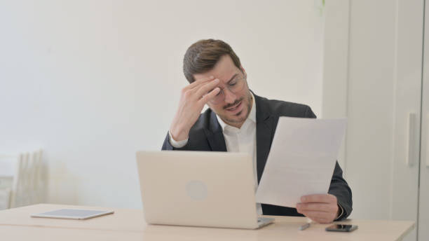 istock Businessman Upset by Loss while Working on Laptop and Documents 1470711323
