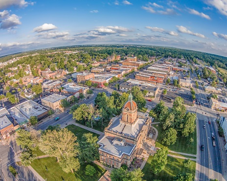 A bustling cityscape featuring a wide road lined with lush trees on both sides