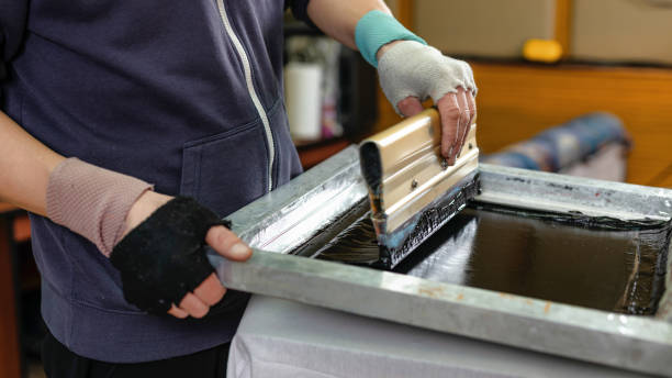 istock silk screen textile printery. male hand with a squeegee. printing by silk screen method in a design studio. creating print on t-shirt in workshop. serigraphy production selective focus photo 1470714360