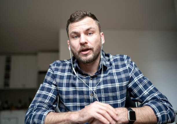 Adult man in earphones vlogging online while at home.