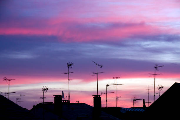 antennas, chimneys and rooftops silhouetted, sunset background. - television aerial roof antenna city imagens e fotografias de stock