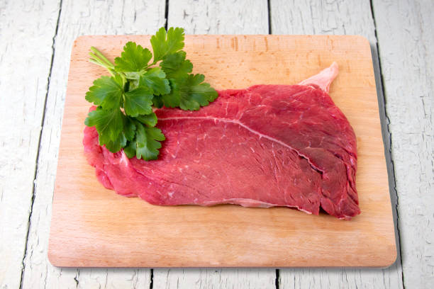istock Raw beef steak on wooden cutting board with parsley 1470718129