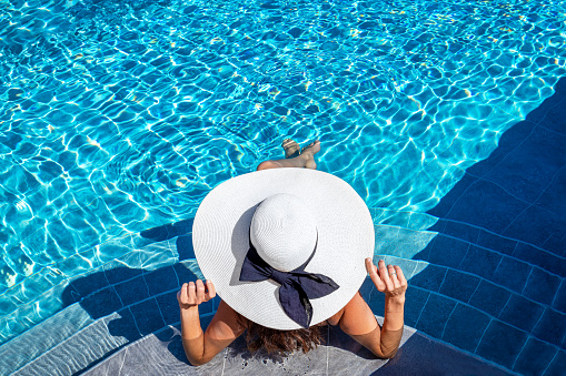 Top view of a woman with sunhat sitting in a swimming pool