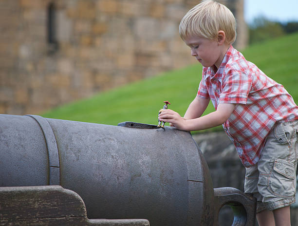 niño jugando en cannon, desde northumberland en castillo de alnwick - cannon alnwick castle alnwick castle fotografías e imágenes de stock