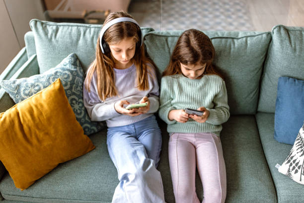 portret dwóch małych dziewczynek ze słuchawkami i telefonem komórkowym - six animals audio zdjęcia i obrazy z banku zdjęć